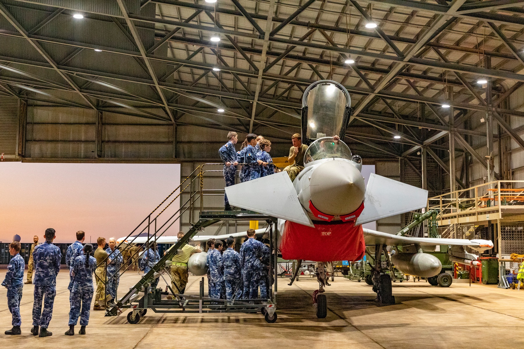 Image shows RAF aviators and Royal Australian Air Force personnel in hangar with Typhoon.